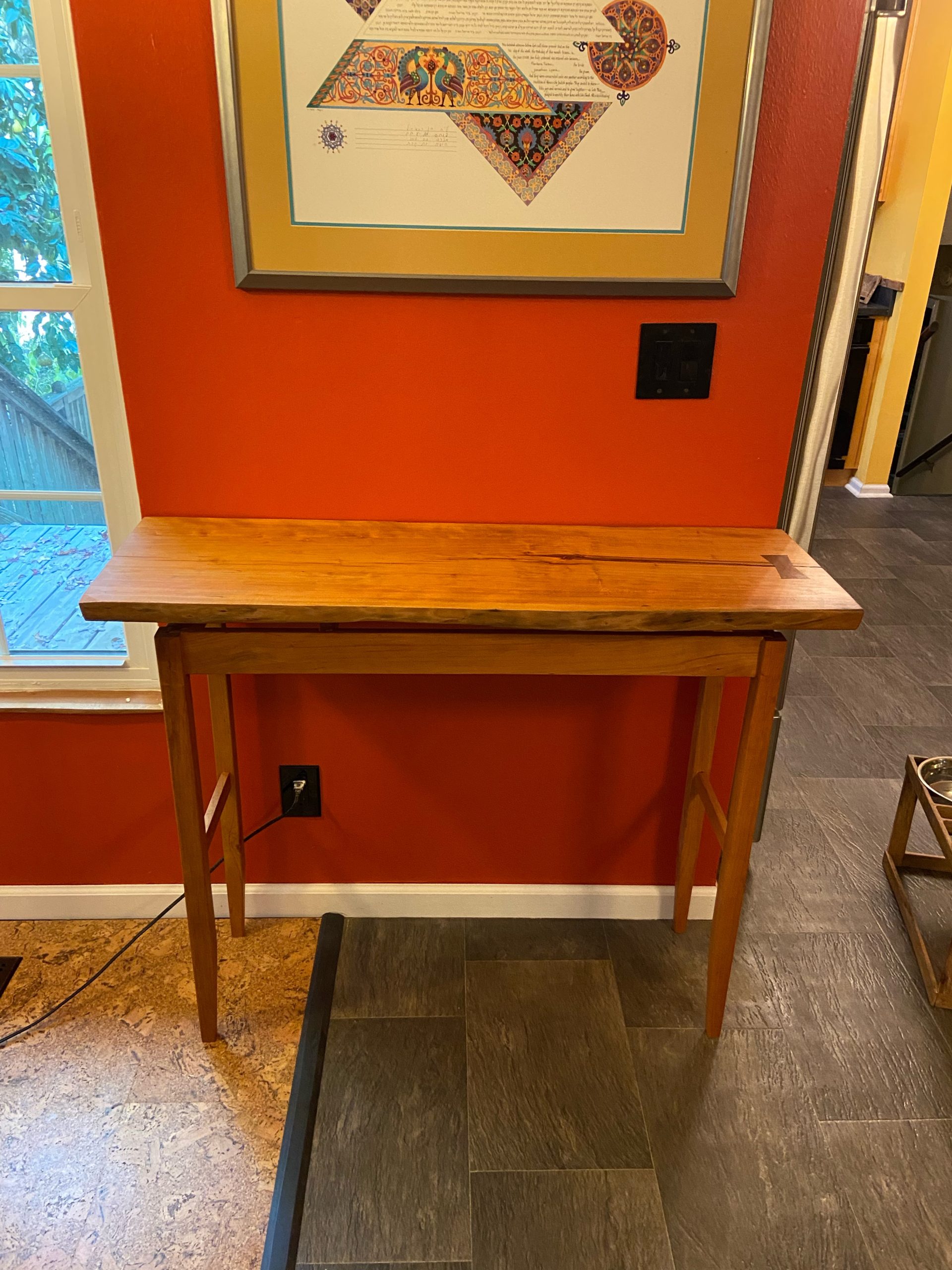 A live cherry slab serves as the top of a floating top table with tapered legs.